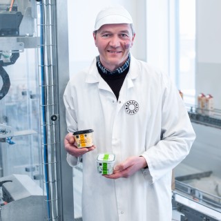 Man in white coat and hat holding cup of sour cream