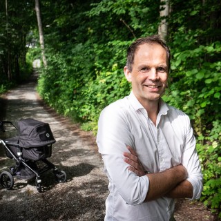 Bilde av en mann med en barnevogn i bakgrunnen