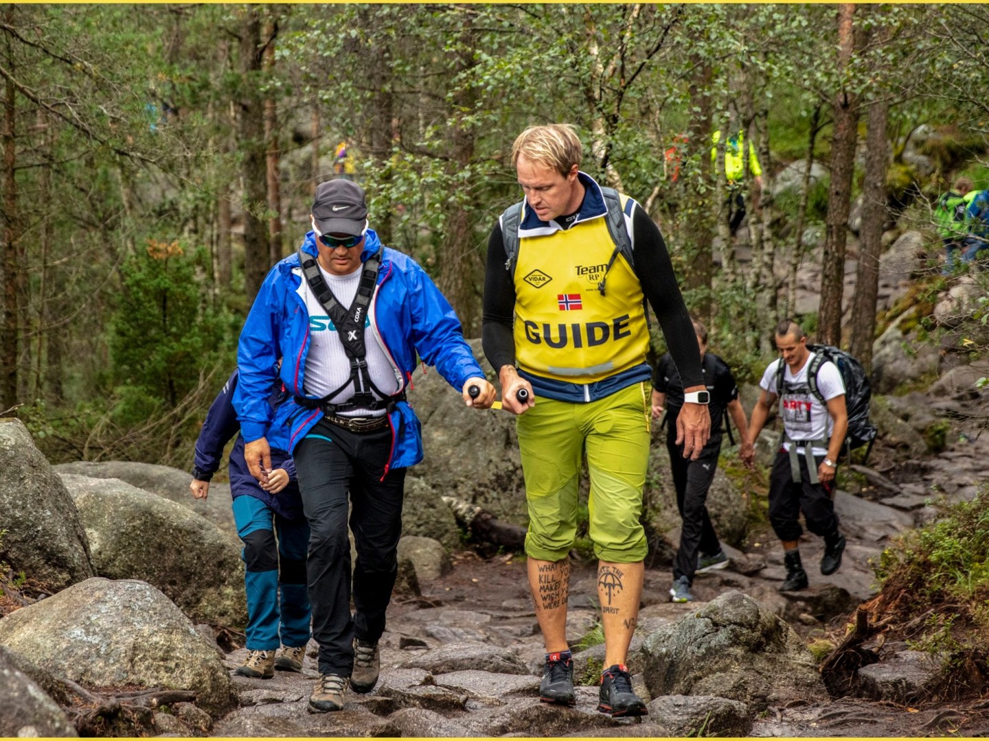 Mann som blir ledsaget av en annen ved at begge holder i en U-formet bøyle.